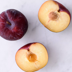 a whole plum and a halved plum