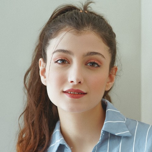Portrait of a woman with cinnamon brown hair, tilting her head sympathetically.